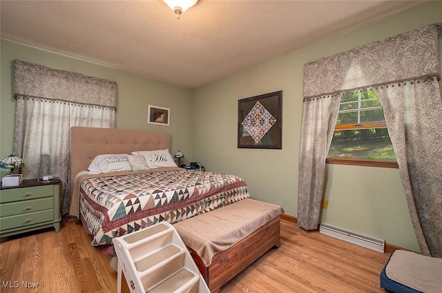 bedroom featuring baseboard heating, wood finished floors, and baseboards