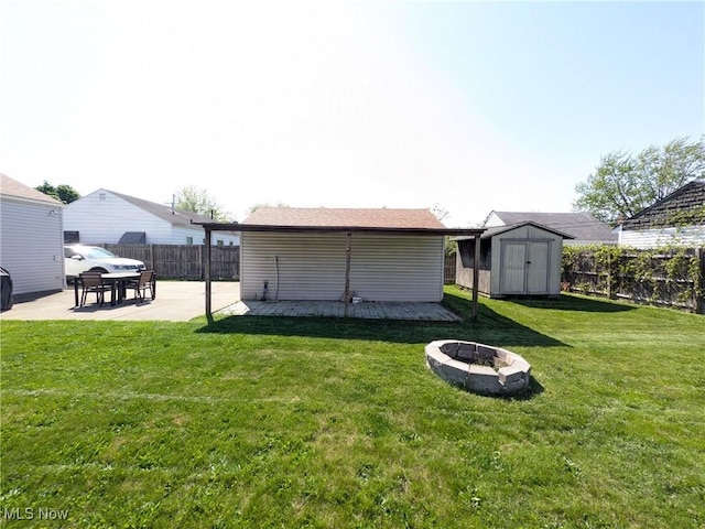 view of yard with a fire pit, a storage shed, a patio, an outdoor structure, and a wooden deck