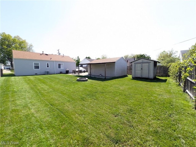 view of yard with an outdoor fire pit, a shed, an outbuilding, and central air condition unit