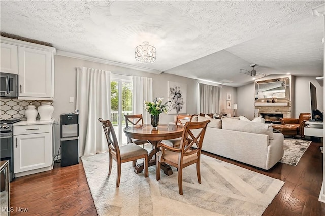4815 Shadow Oak Dr, Austintown, OH 44515 - dining room with wood finished floors, a textured ceiling, a stone fireplace, ceiling fan, and a chandelier