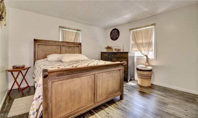 bedroom featuring dark wood-style flooring, baseboards, and a textured ceiling