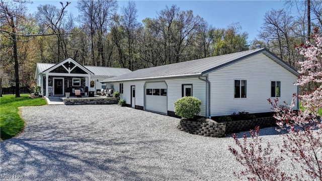 single story home with a garage, an outdoor structure, metal roof, and driveway