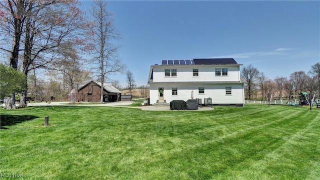 rear view of house featuring a yard, an outdoor structure, and a playground