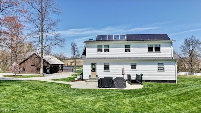 rear view of house with entry steps, roof mounted solar panels, and an outdoor structure