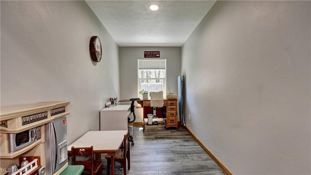 hallway with dark wood-type flooring, an office area, and baseboards