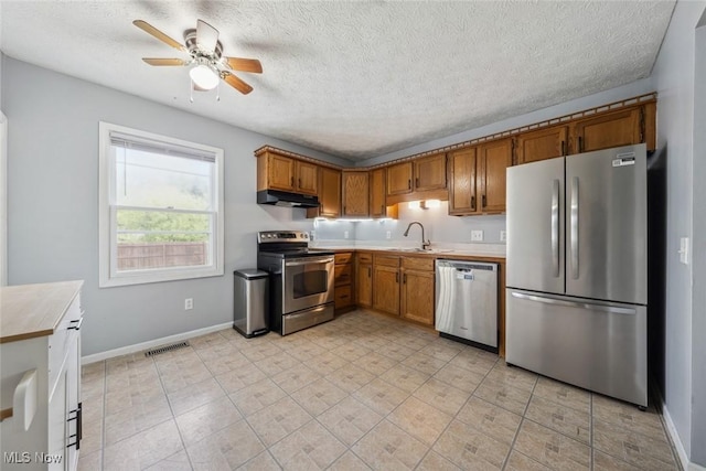 kitchen featuring appliances with stainless steel finishes, under cabinet range hood, a sink, a ceiling fan, and light countertops