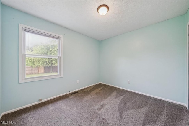 carpeted empty room with baseboards and a textured ceiling