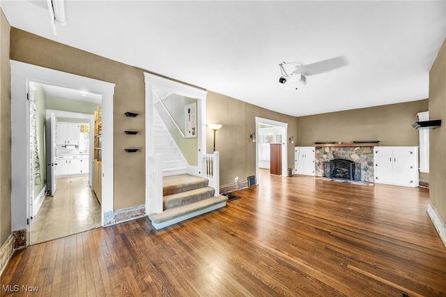26561 Butternut Ridge Rd, North Olmsted, OH 44070 - unfurnished living room with hardwood / wood-style flooring, stairs, a stone fireplace, and baseboards