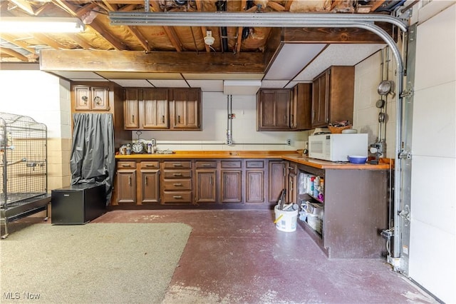 73 Hemlock Ln, Weirton, WV 26062 - kitchen featuring white microwave, concrete floors, concrete block wall, and butcher block counters