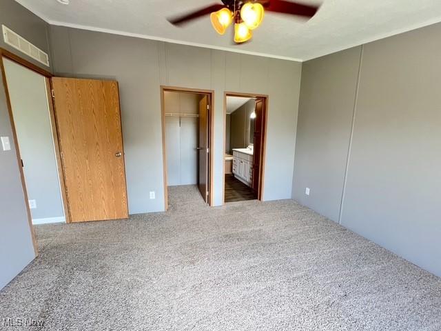 8248 Lappin Ln NE, Mineral City, OH 44656 - unfurnished bedroom featuring carpet floors, ornamental molding, a walk in closet, ensuite bath, and ceiling fan