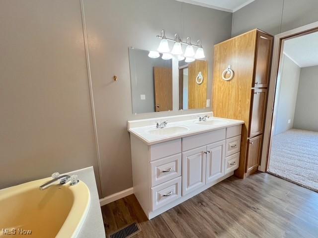 8248 Lappin Ln NE, Mineral City, OH 44656 - bathroom with wood finished floors, a bath, double vanity, and crown molding