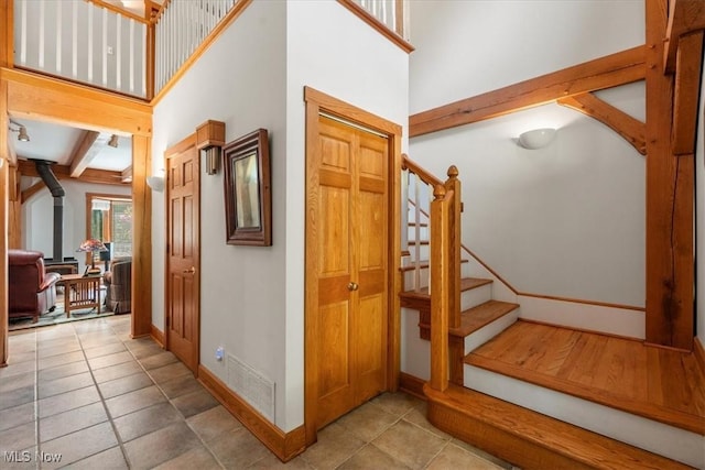 70 Northlake Ct, Vincent, OH 45784 - staircase featuring a wood stove, baseboards, a high ceiling, tile patterned floors, and beamed ceiling
