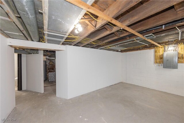 unfinished basement featuring electric panel and concrete block wall