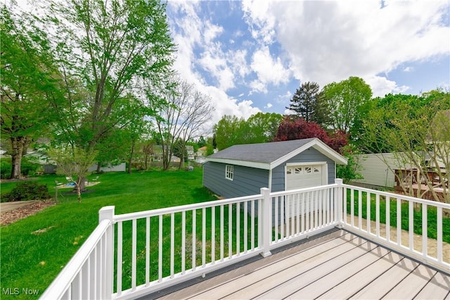 wooden terrace featuring a detached garage, an outbuilding, and a lawn