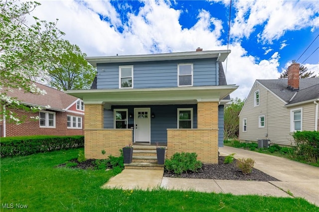 view of front of house featuring brick siding, central AC, covered porch, and a front yard