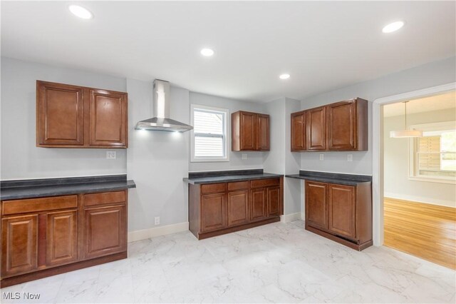 kitchen with wall chimney range hood, dark countertops, light marble finish floors, recessed lighting, and baseboards