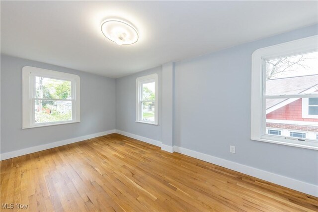 unfurnished room featuring plenty of natural light, light wood-style floors, and baseboards