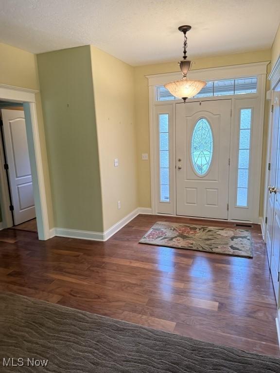 entryway with dark wood-type flooring and baseboards
