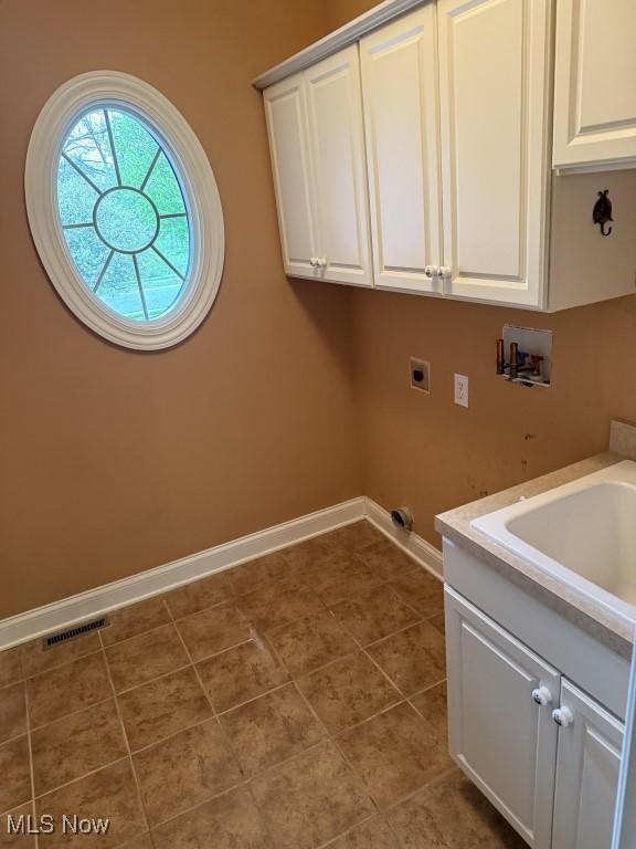 washroom with washer hookup, baseboards, cabinet space, electric dryer hookup, and tile patterned flooring