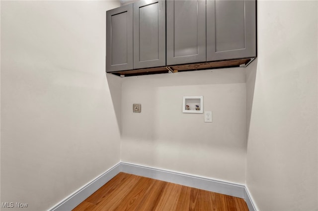 washroom with cabinet space, baseboards, hookup for a washing machine, and light wood-style floors