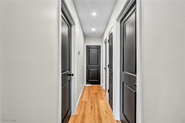 corridor with light wood-type flooring and baseboards