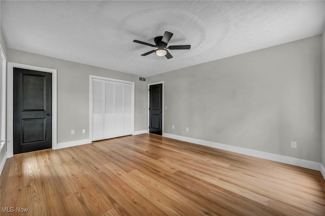 unfurnished bedroom with baseboards, light wood-style floors, a textured ceiling, and ceiling fan