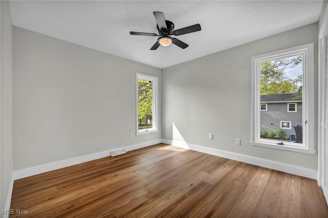 empty room with baseboards, wood finished floors, and a ceiling fan