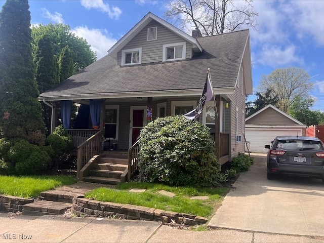 view of front of home with a detached garage, a shingled roof, covered porch, and an outbuilding