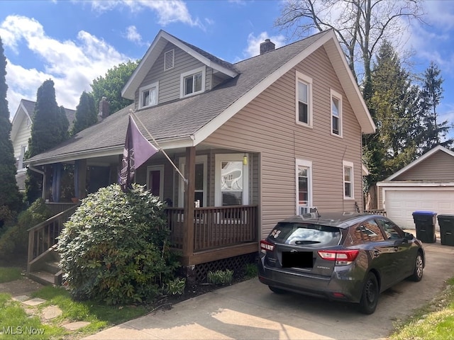 view of front of home featuring a porch, a chimney, a shingled roof, and an outdoor structure