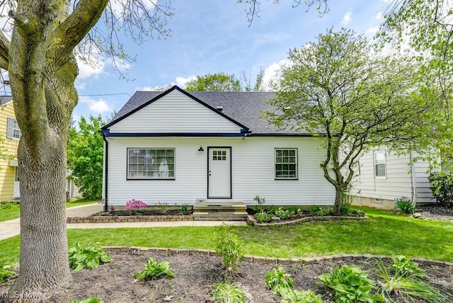 bungalow-style home featuring a front lawn and roof with shingles