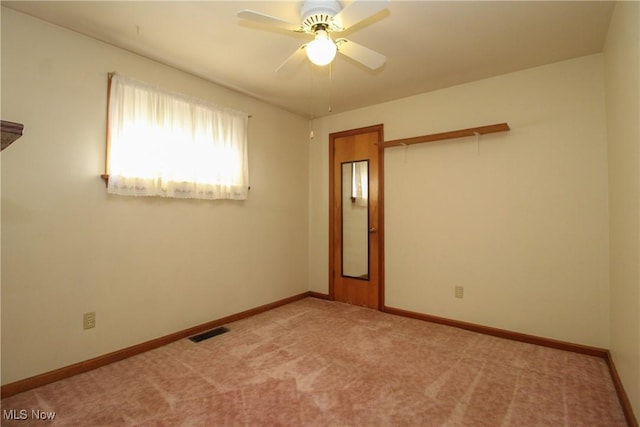 carpeted spare room featuring baseboards and ceiling fan