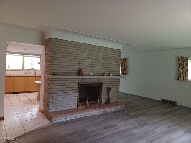 1050 Park Cir, Girard, OH 44420 - unfurnished living room with a brick fireplace, light wood-style flooring, baseboards, and a sink
