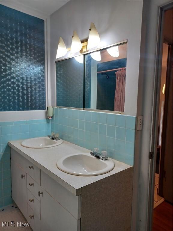 1050 Park Cir, Girard, OH 44420 - bathroom featuring double vanity, backsplash, and tile walls