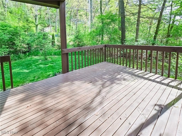 wooden terrace featuring a yard and a forest view