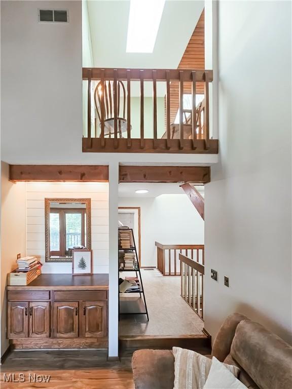 stairway featuring a towering ceiling, a skylight, and wood finished floors
