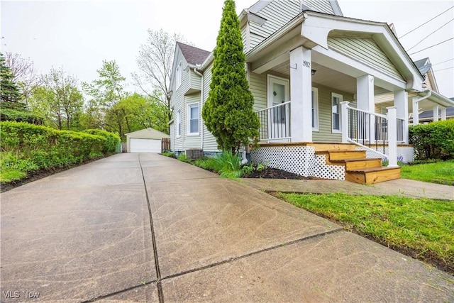 view of front of property with covered porch, a detached garage, and an outdoor structure