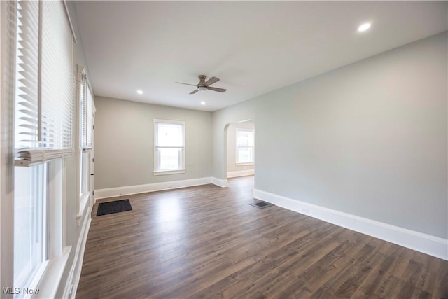 unfurnished room with arched walkways, ceiling fan, baseboards, dark wood-type flooring, and recessed lighting