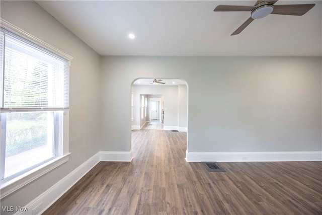 unfurnished room with ceiling fan, arched walkways, wood finished floors, baseboards, and recessed lighting