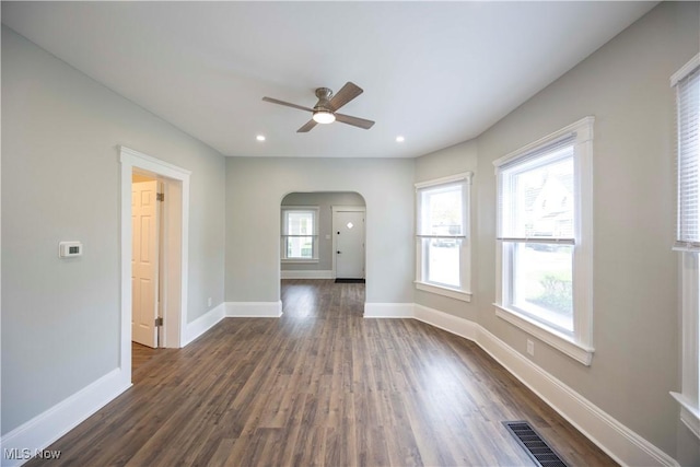unfurnished room with arched walkways, a ceiling fan, dark wood finished floors, baseboards, and recessed lighting