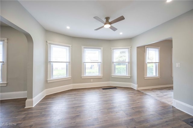 spare room featuring ceiling fan, arched walkways, wood finished floors, baseboards, and recessed lighting