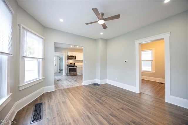 unfurnished living room featuring plenty of natural light, dark wood finished floors, a ceiling fan, baseboards, and recessed lighting
