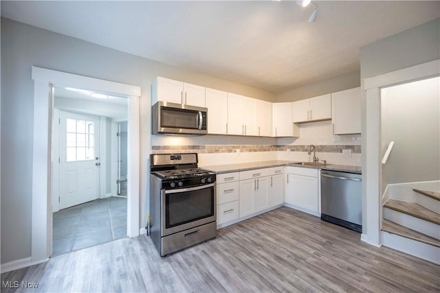 kitchen featuring stainless steel appliances, a sink, white cabinets, and light wood finished floors