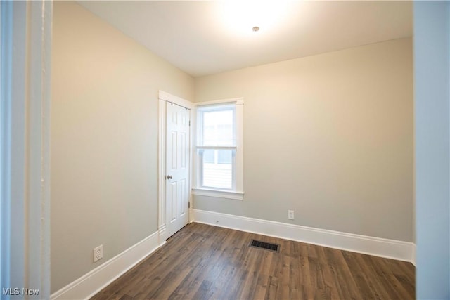 spare room with baseboards and dark wood-style floors