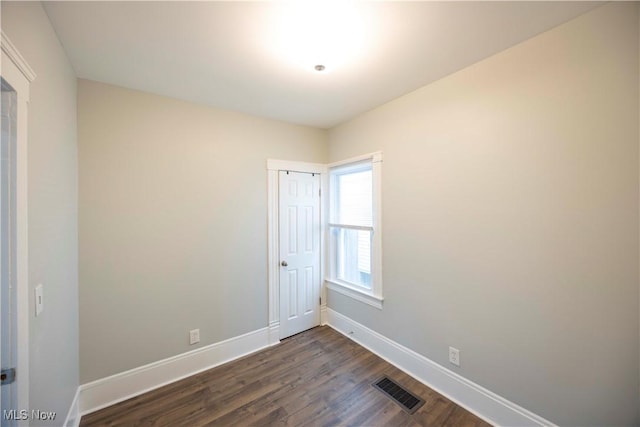 spare room featuring dark wood finished floors and baseboards