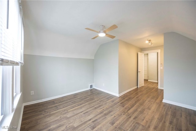 additional living space with lofted ceiling, a ceiling fan, dark wood-type flooring, and baseboards