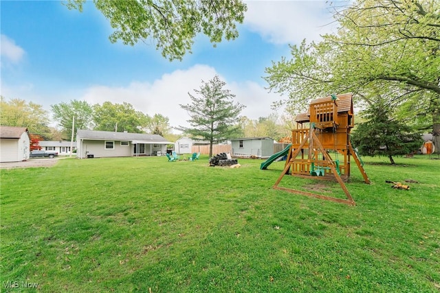 view of green lawn featuring a playground, a shed, and an outbuilding