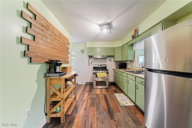 kitchen with green cabinets, stainless steel appliances, a sink, dark wood-type flooring, and a textured ceiling