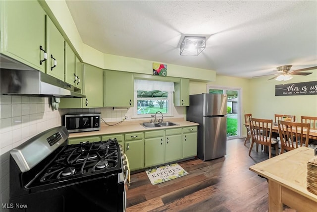 kitchen with green cabinets, appliances with stainless steel finishes, a sink, under cabinet range hood, and a textured ceiling