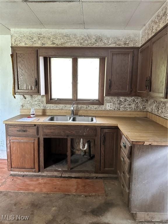 kitchen featuring a sink, light countertops, concrete floors, and dark brown cabinets