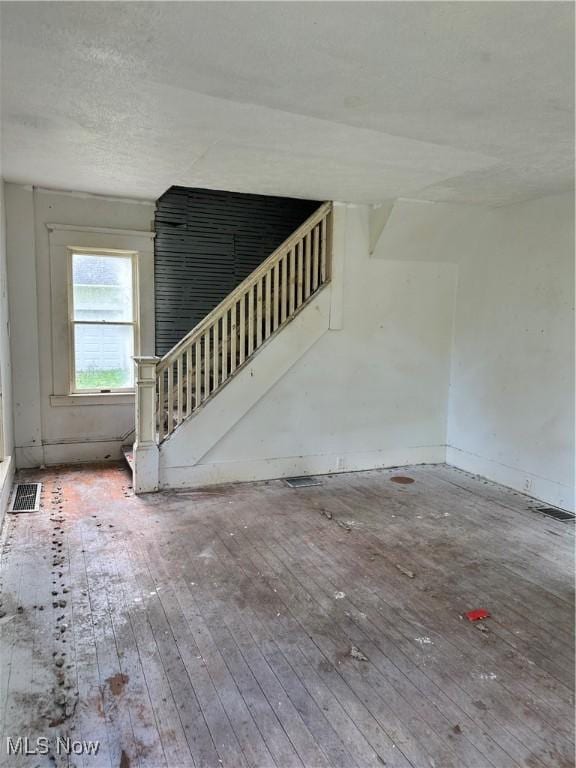 unfurnished living room featuring wood-type flooring and stairs